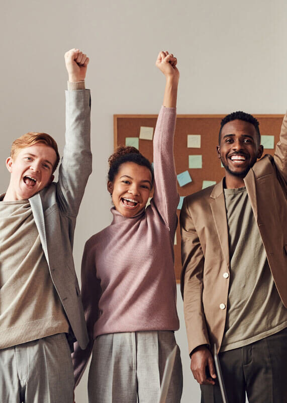 Three people holding a hand high with pride.