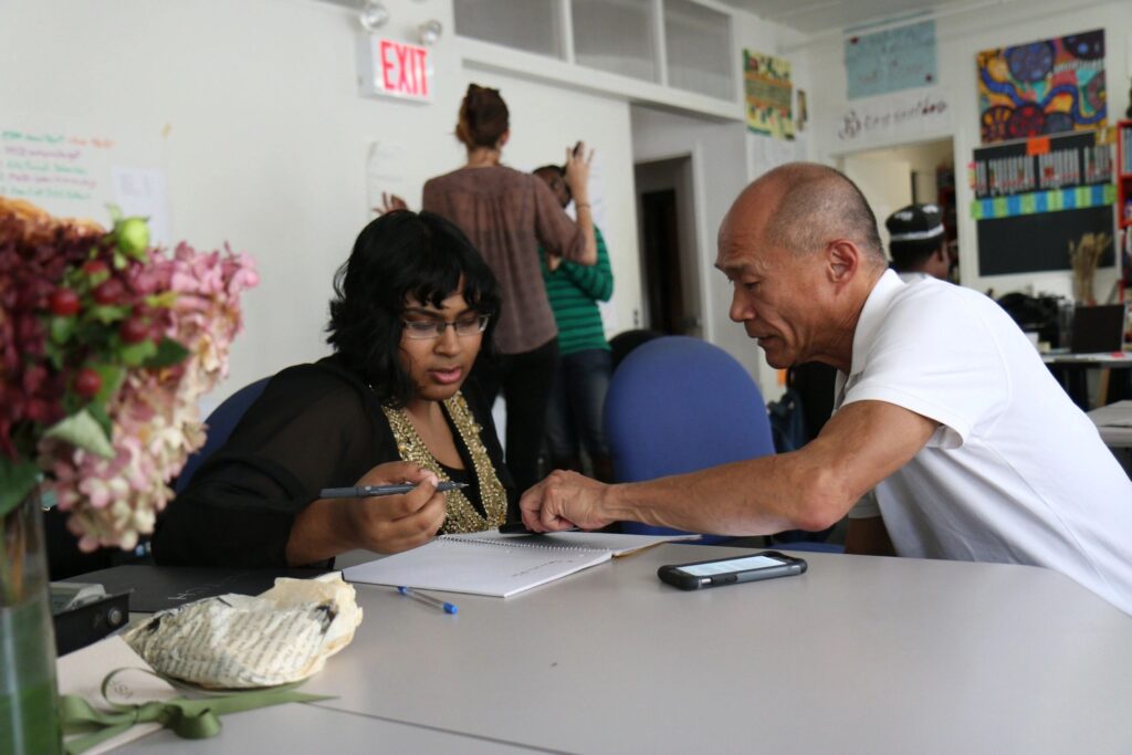 Man helping a woman fill out paperwork.