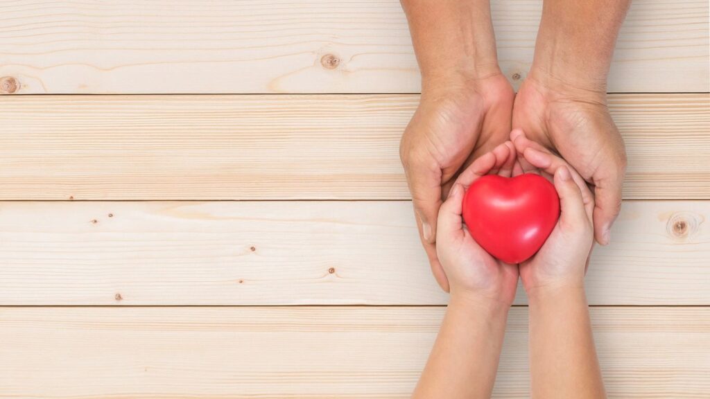 Four hands, holding a heart.